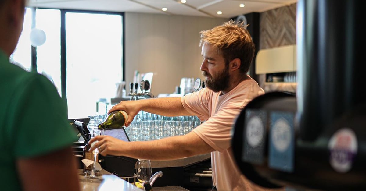 Bar tender pouring a glass of bubbles for a customer