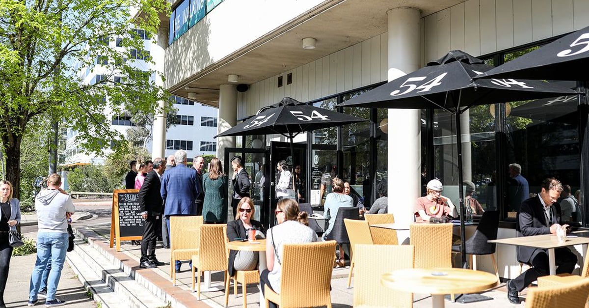 A busy cafe with lots of people sitting in the outdoor seating areas