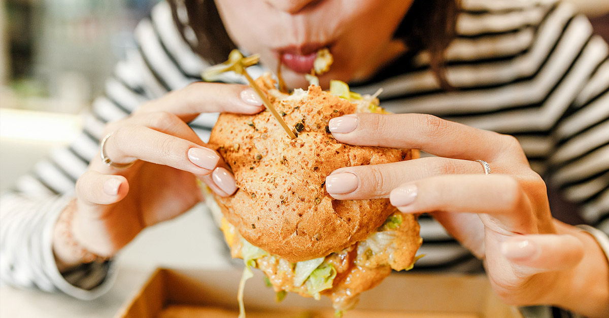 Lady eating a home delivered gourmet burger