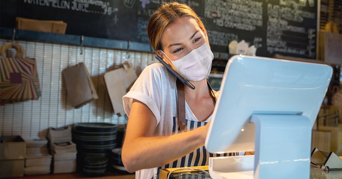 Waitress in a restaurant multitasking; taking phone calls and putting an order into the POS system 