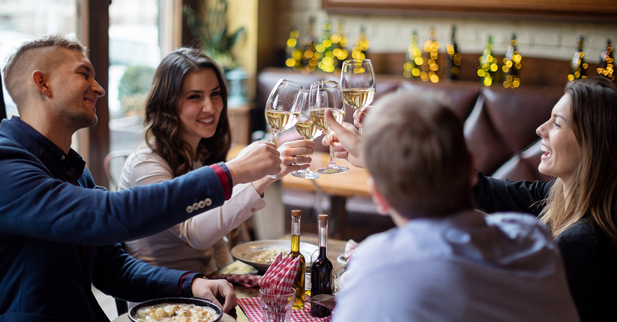 A group of friends celebrating, clinking their wine glasses together in a restaurant 