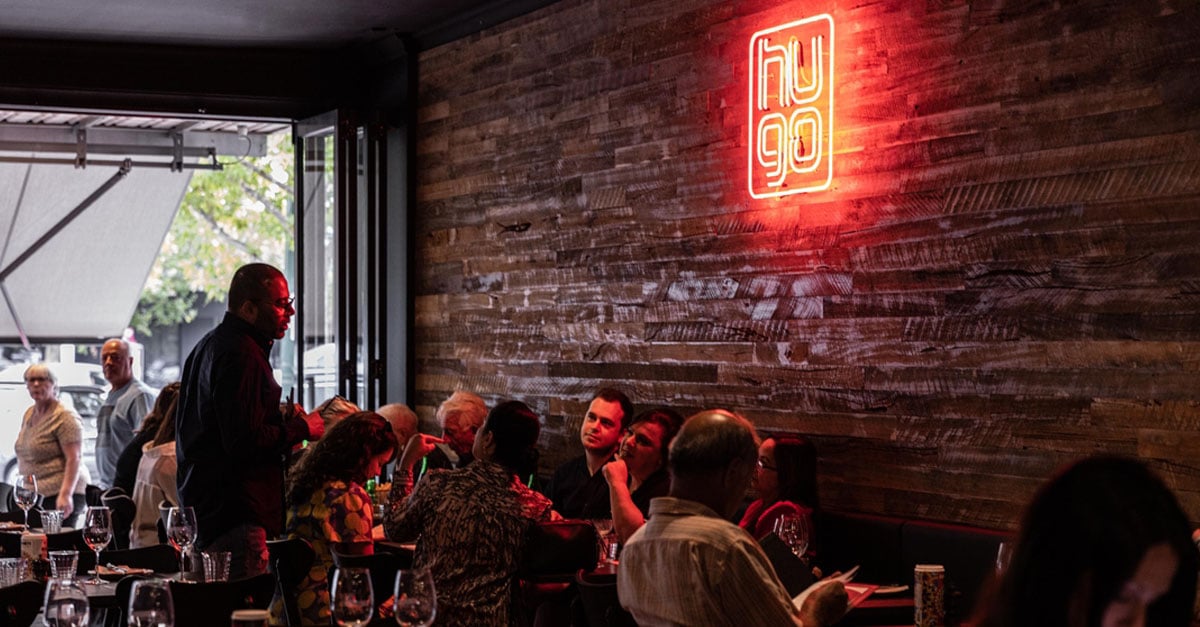 Waiter taking customers order in busy restaurant