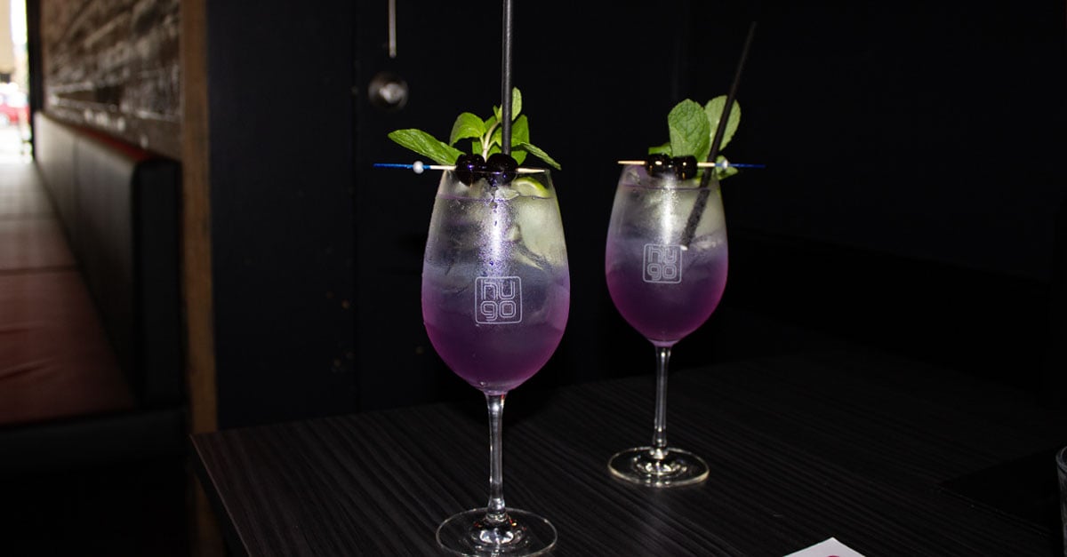 two purple gin cocktails sitting on a table in restaurant