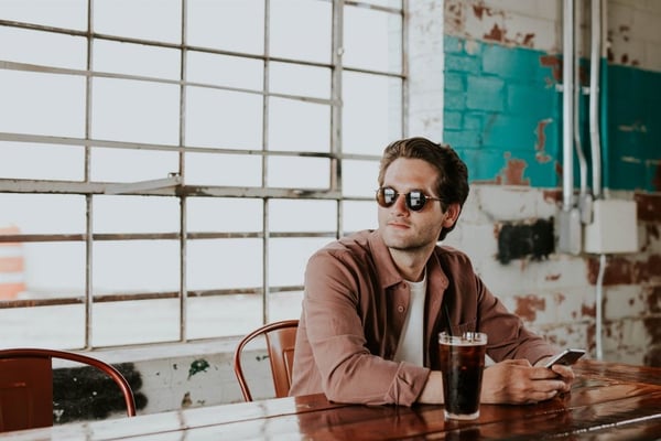 man in glasses using mobile to orde in a restaurant