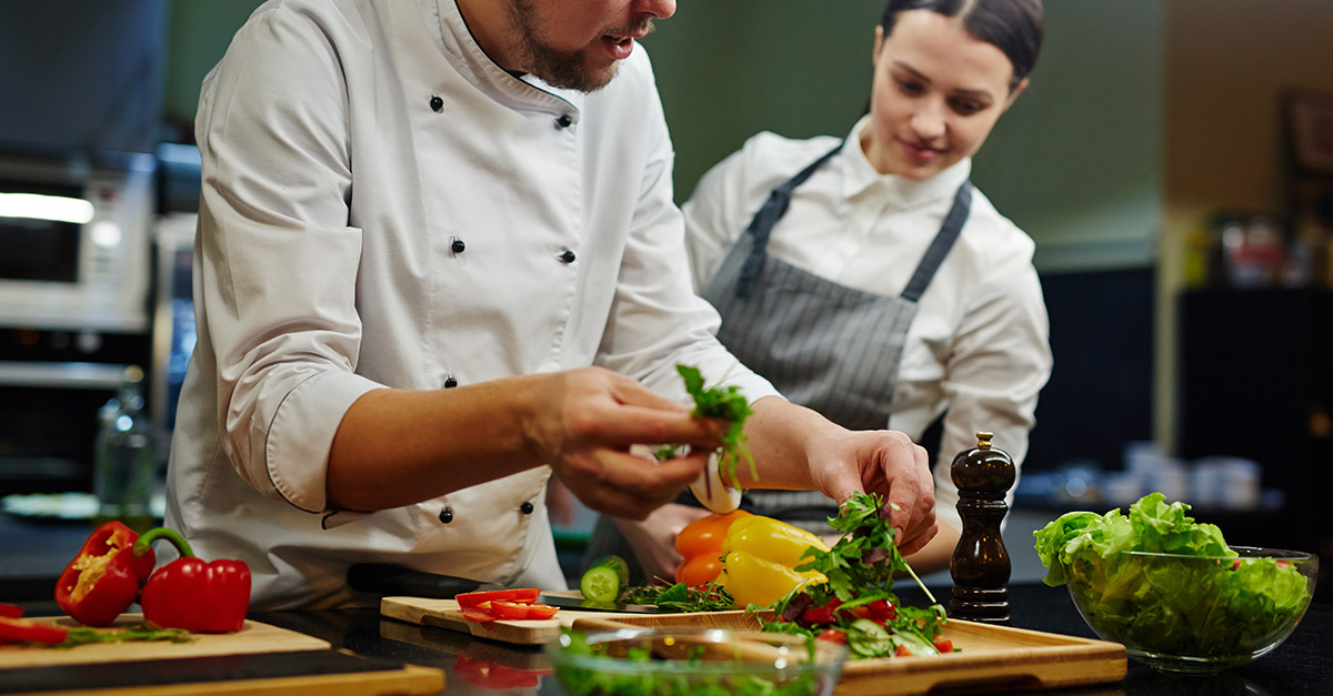 Chef cooking with fresh produce in kitchen