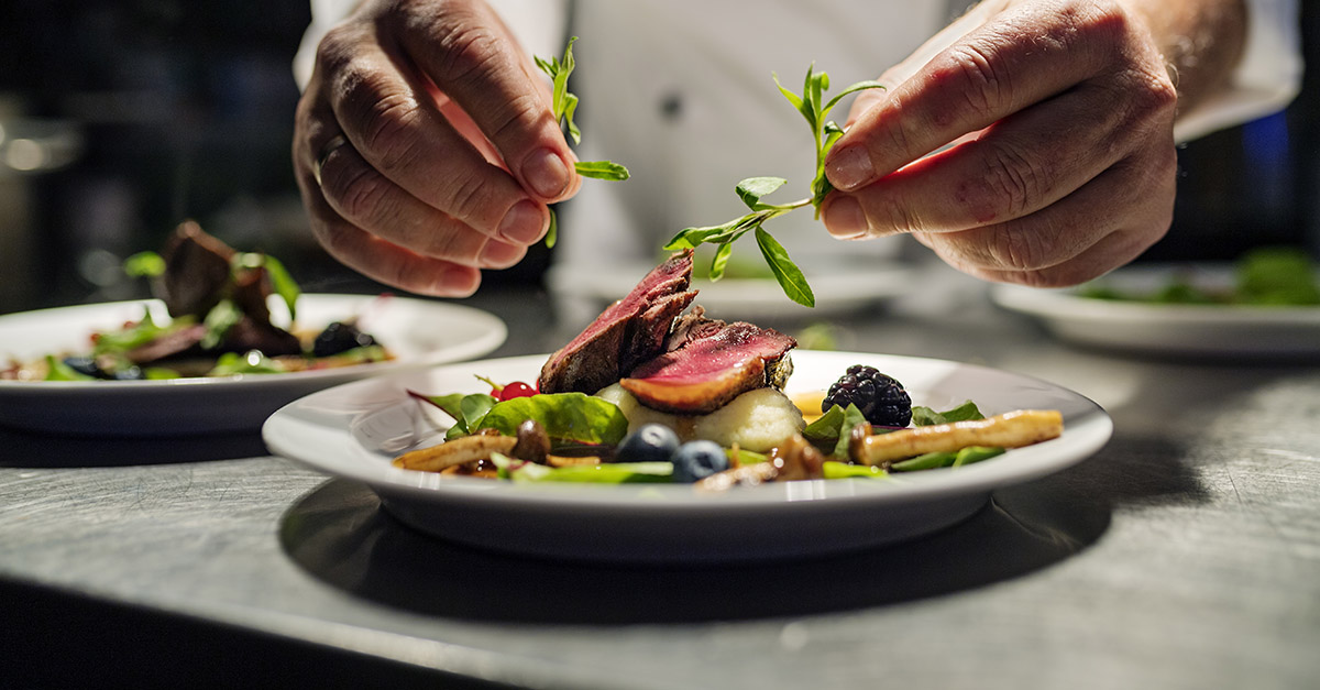 Chef finishing a fine-dining dish in a kitchen