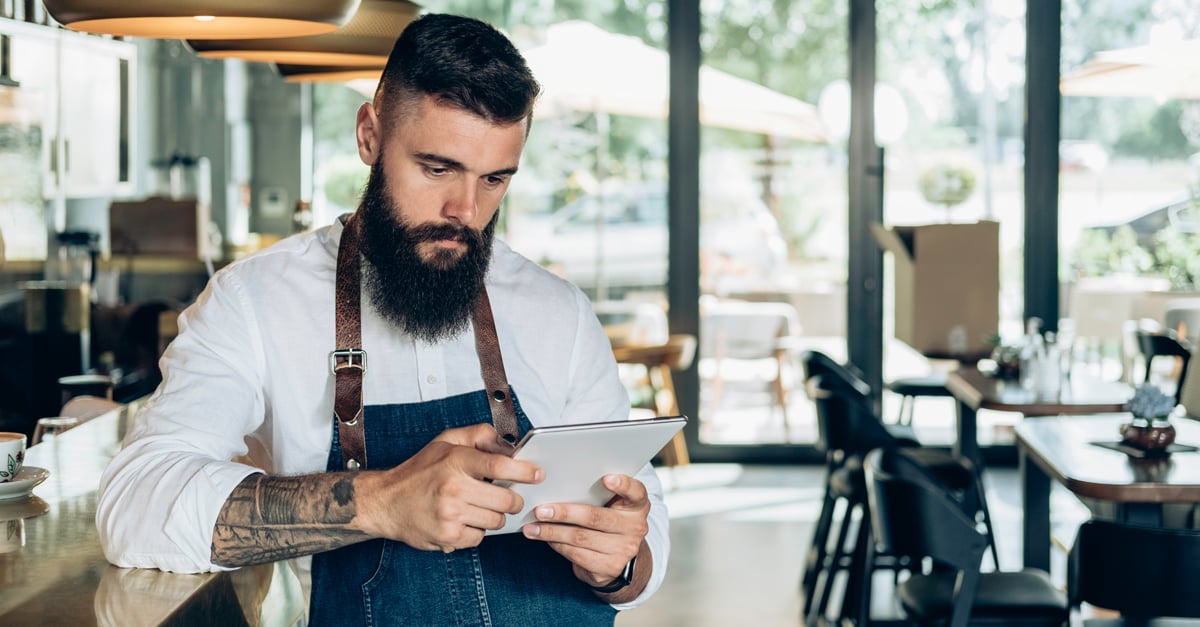 hospitality operator in his restaurant looking at his ipad