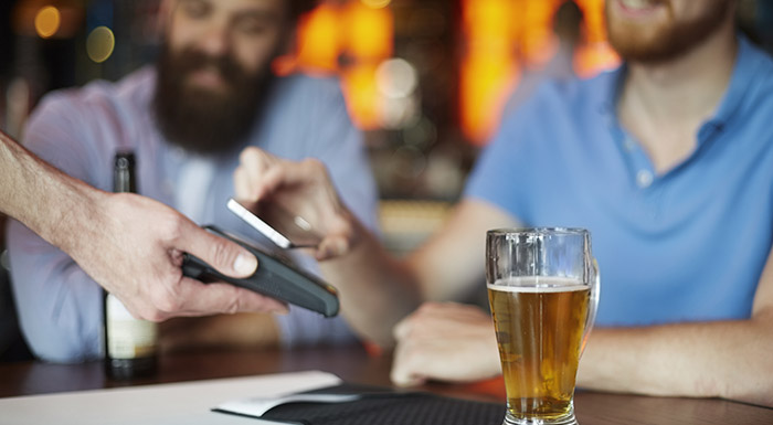 Customer paying for bar tab with mobile at the bar