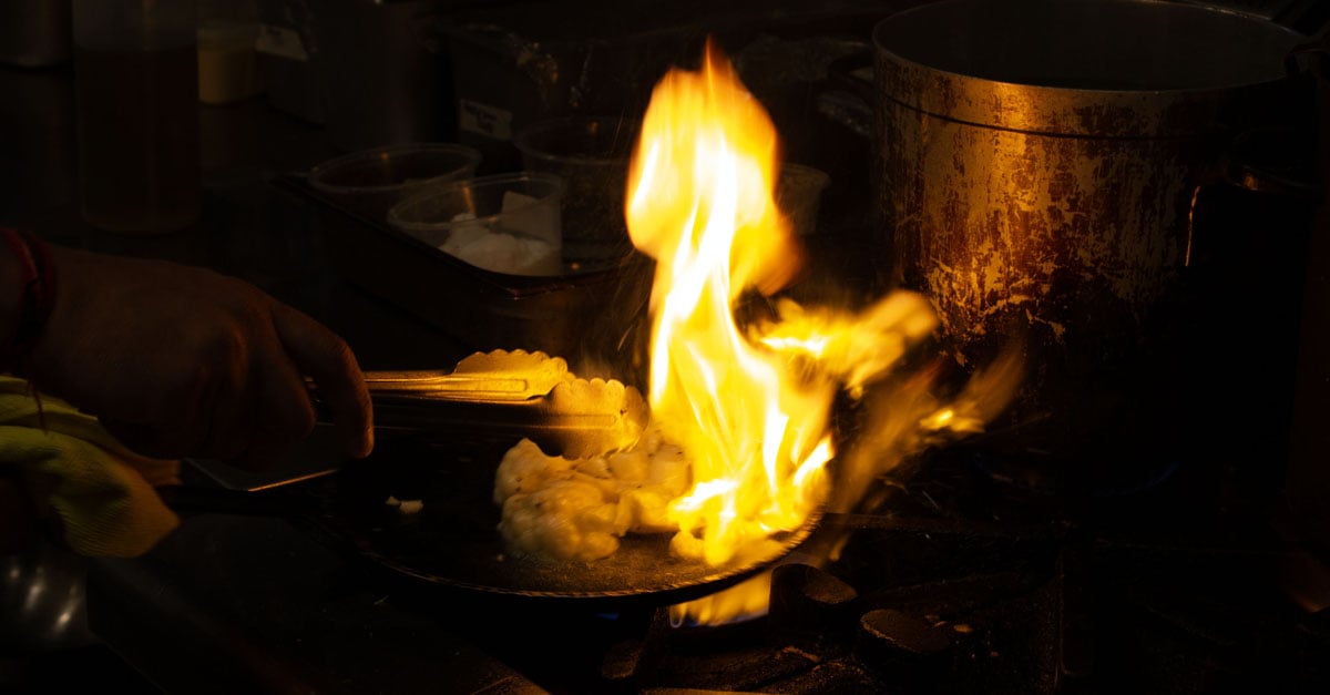 Cauliflower steak being cooked on a hot pan with big flames