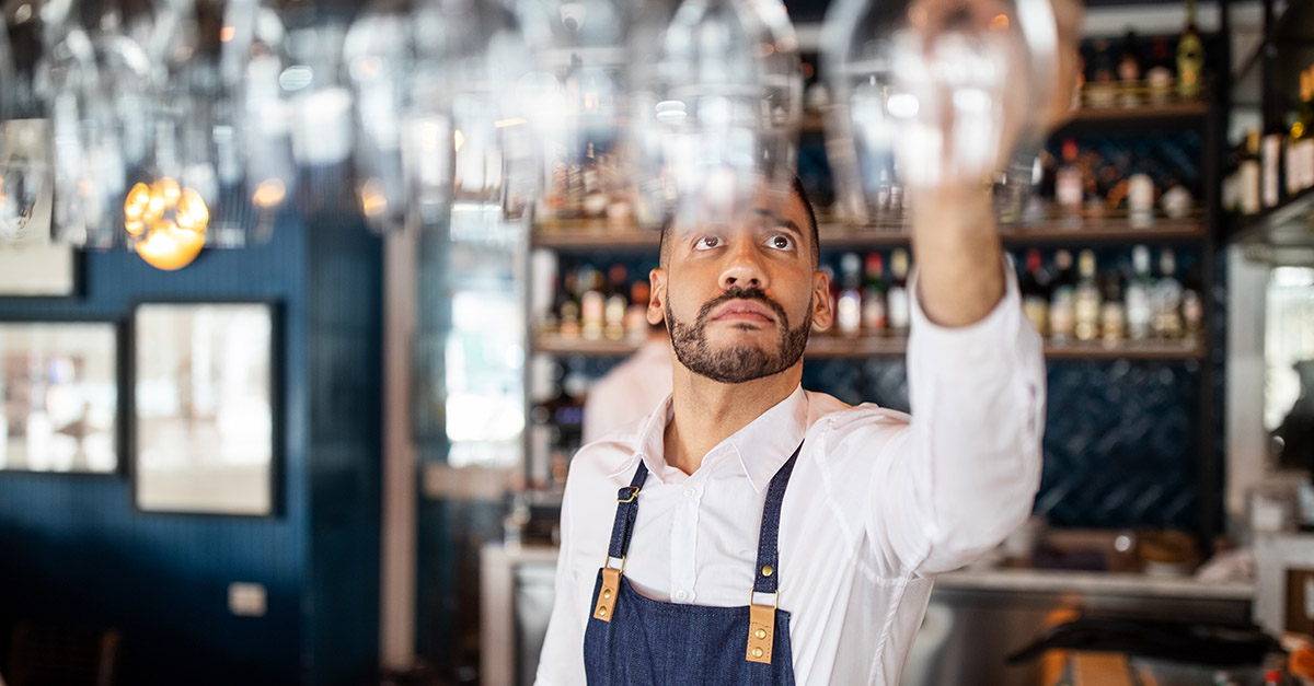 Staff member hanging glasses in a bar