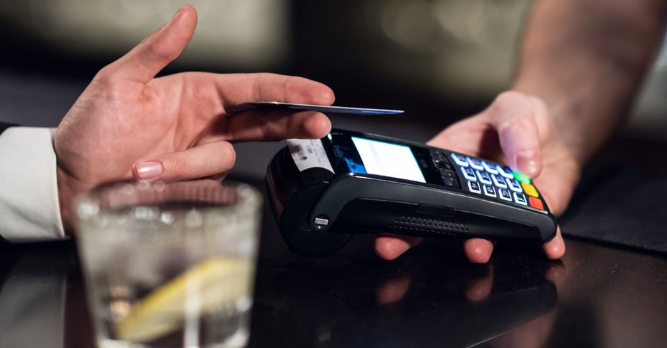 customer paying in a restaurant by tapping their card on EFTPOS terminal 