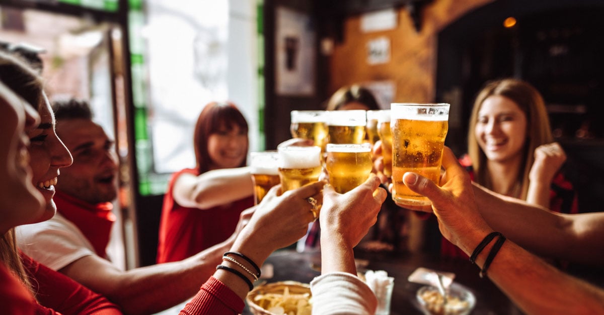 A group of friends in a bar celebrating the footy finals with beers