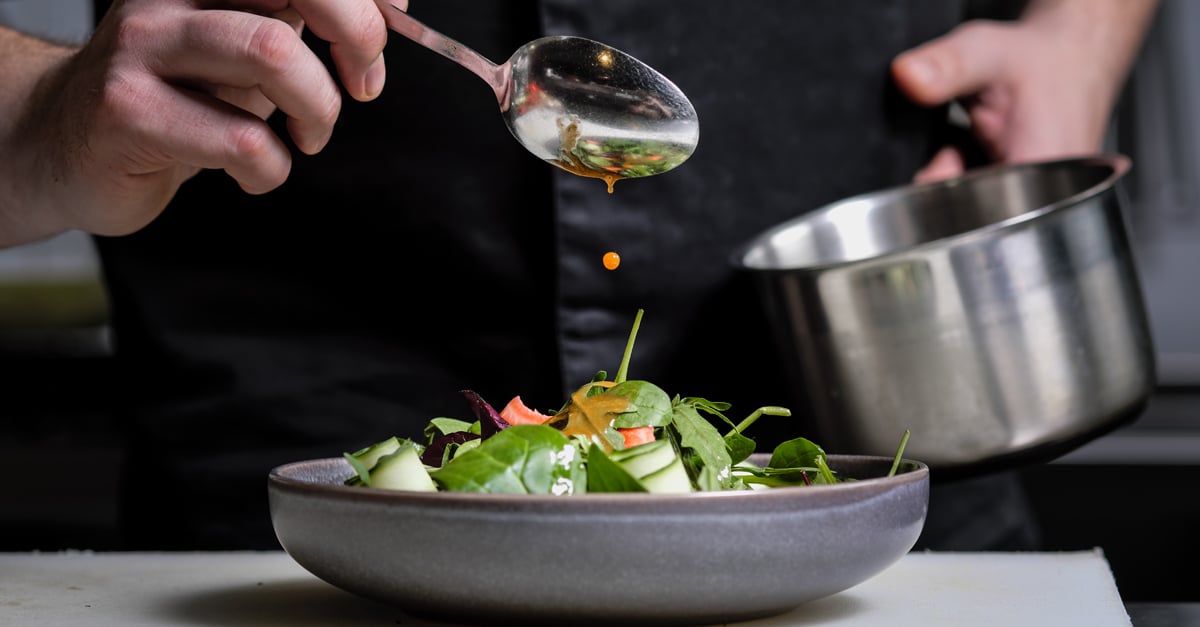 Chef pouring sauce over a dish