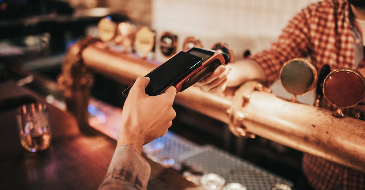 customer paying at a bar for their drinks with their phone via tap and pay