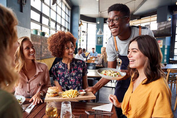 Waiter bringing out food to happy customers