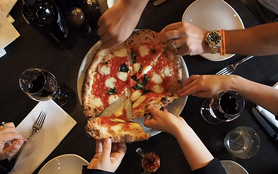 Overhead shot of a table and everyone taking a slice of pizza