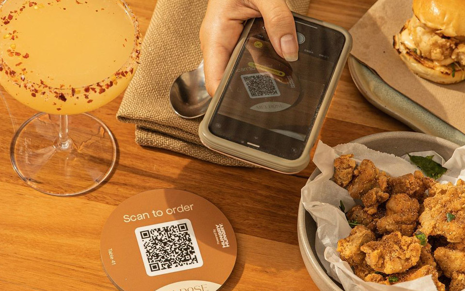 Restaurant customer scanning table QR code with their phone to access the online menu and order food and drinks 